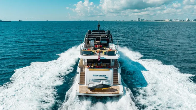 Slide: The Image of 2018 Sanlorenzo SL106 yacht cruising on open sea with city skyline in background. - 5