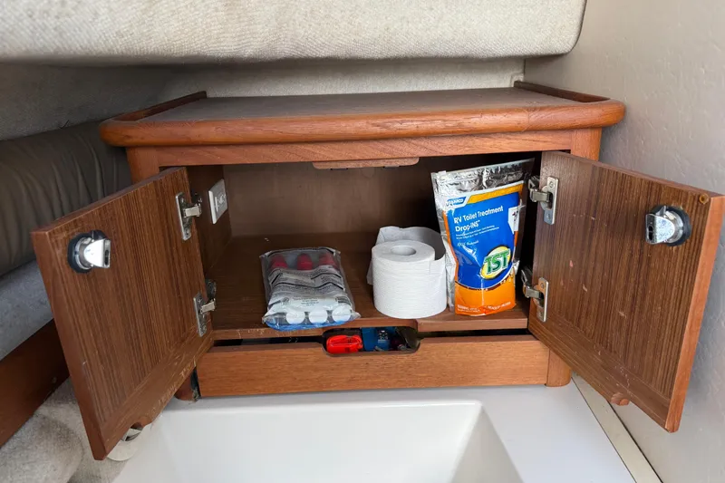 Slide: The Image of Open wooden cabinet on 2005 Glacier Bay 2680 Coastal Runner, storing toilet paper and cleaning supplies. - 45