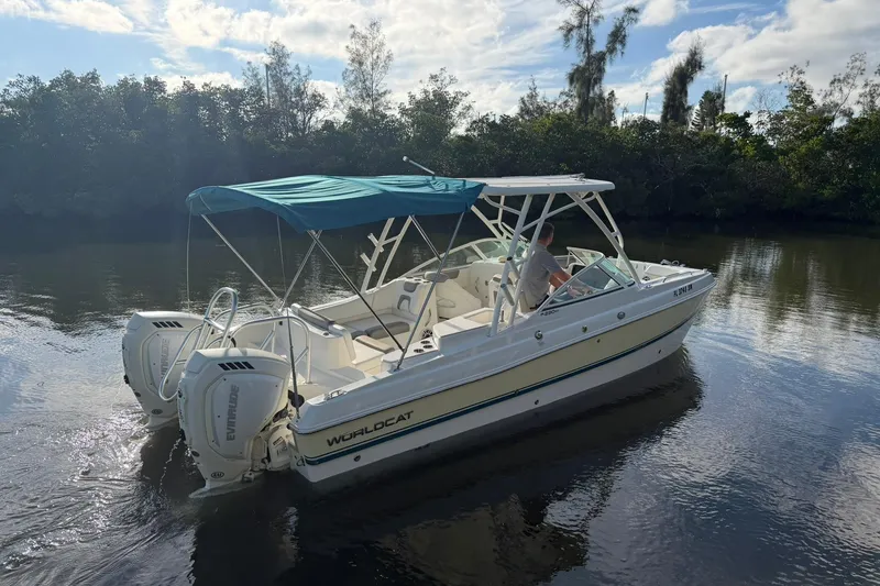 Slide: The Image of 2020 World Cat 230 SD boat with canopy on calm water, surrounded by trees. - 24