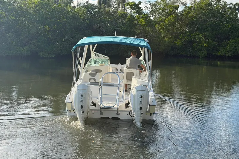 Slide: The Image of 2020 World Cat 230 SD boat navigating a calm river with lush greenery. - 25