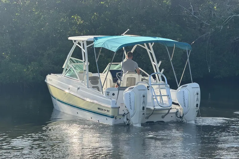 Slide: The Image of 2020 World Cat 230 SD boat with dual engines and blue canopy on calm water. - 27