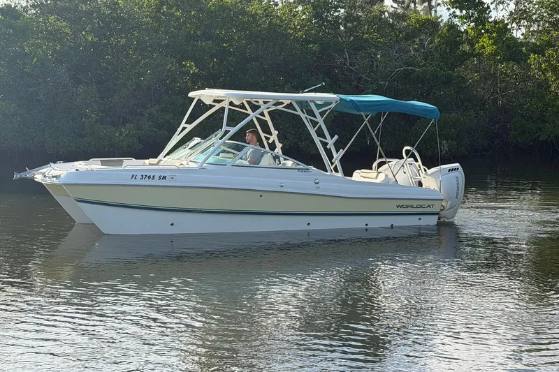 Slide: The Image of 2020 World Cat 230 SD boat cruising on calm water with lush greenery background. - 30