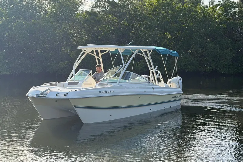 Slide: The Image of 2020 World Cat 230 SD boat cruising on a calm river with lush greenery. - 31