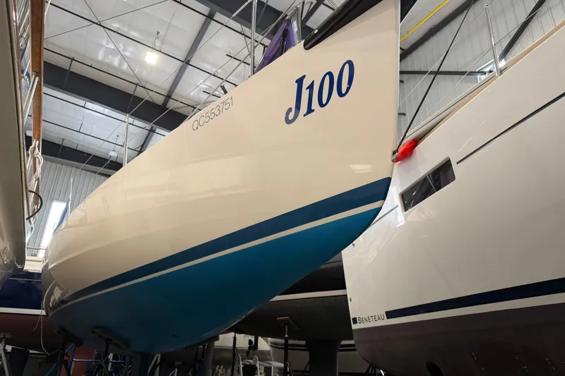Slide: The Image of 2006 J Boats J/100 sailboat in storage, showcasing sleek design and blue stripe. - 16