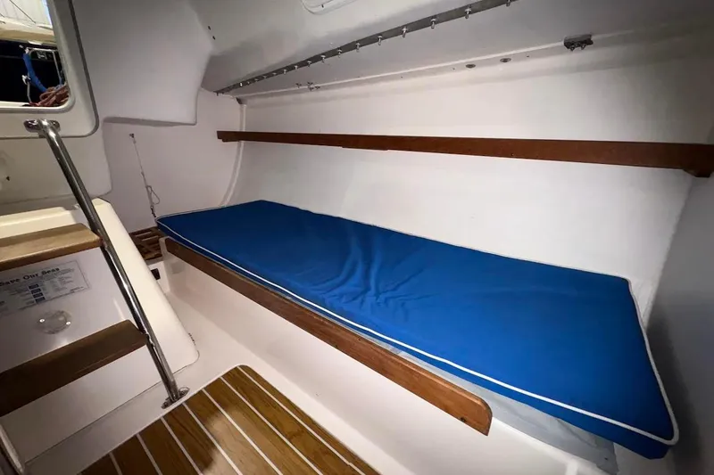 Slide: The Image of Interior of 2006 J Boats J/100 sailboat with blue cushioned berth and wooden accents. - 26