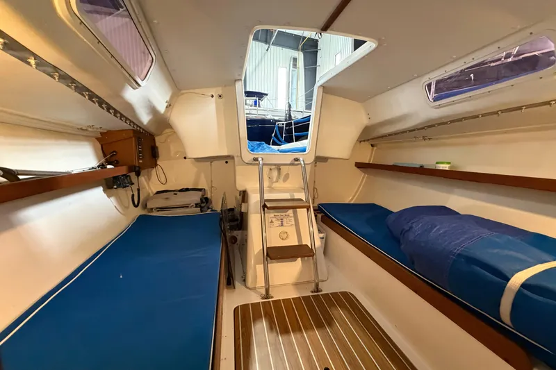 Slide: The Image of Interior of 2006 J Boats J/100 sailboat, featuring blue cushions and wooden accents. - 34