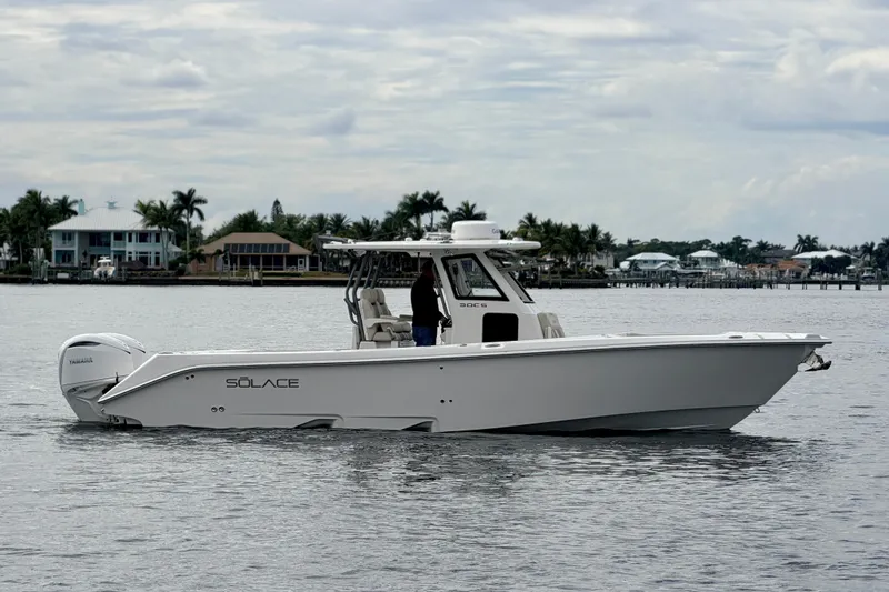 Slide: The Image of 2026 Solace 30 CS boat on calm water with coastal homes in background. - 10