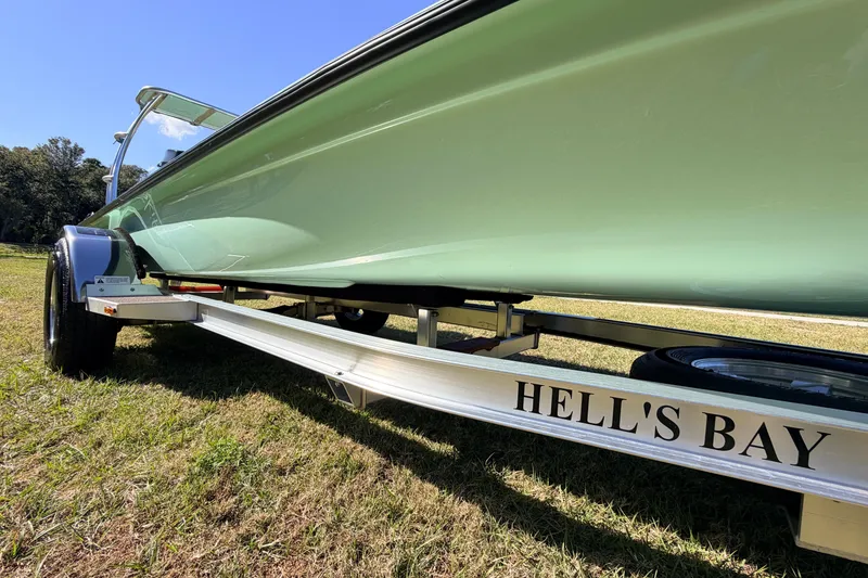 Slide: The Image of 2011 Hell's Bay Glades Skiff on trailer, green hull, sunny outdoor setting. - 13