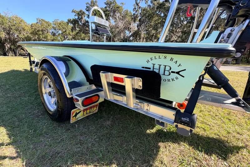 Slide: The Image of 2011 Hell's Bay Glades Skiff on trailer, parked on grass, showcasing logo and design. - 15