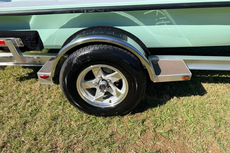 Slide: The Image of 2011 Hell's Bay Glades Skiff trailer wheel on grass, showcasing sleek design. - 19