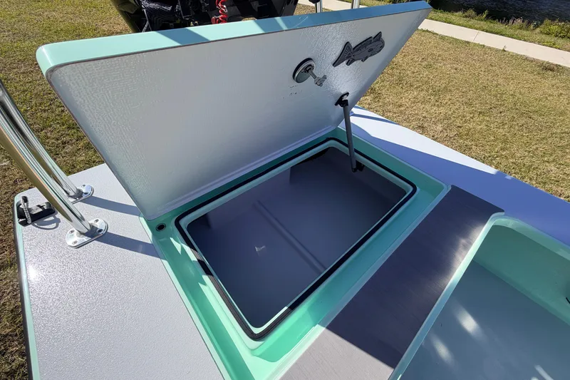 Slide: The Image of 2011 Hell's Bay Glades Skiff storage compartment open on grassy area. - 39