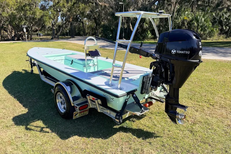 Slide: The Image of 2011 Hell's Bay Glades Skiff with Tohatsu motor on trailer, parked on grass. - 4