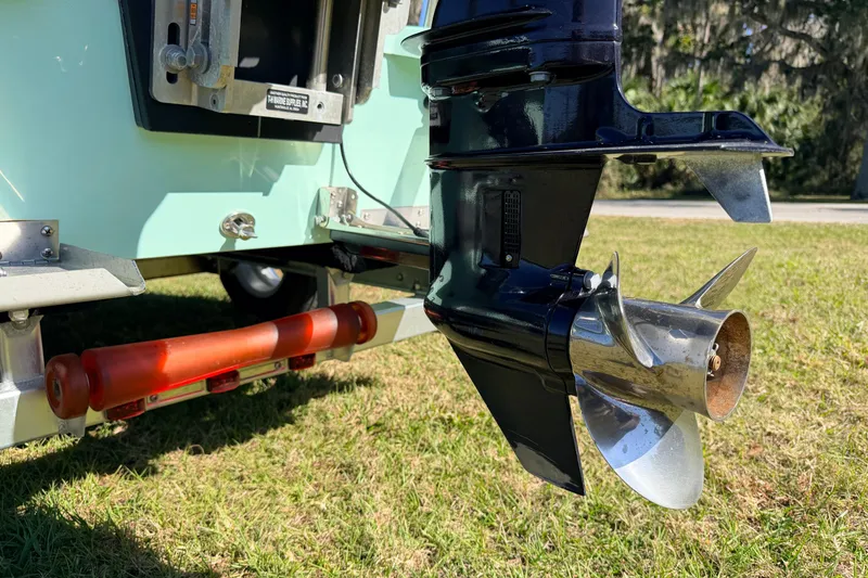 Slide: The Image of 2011 Hell's Bay Glades Skiff boat propeller on grass, showcasing rear motor detail. - 54