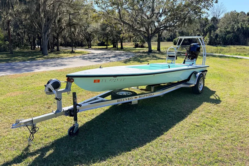 Slide: The Image of 2011 Hell's Bay Glades Skiff on trailer, parked on grassy area with trees in background. - 6
