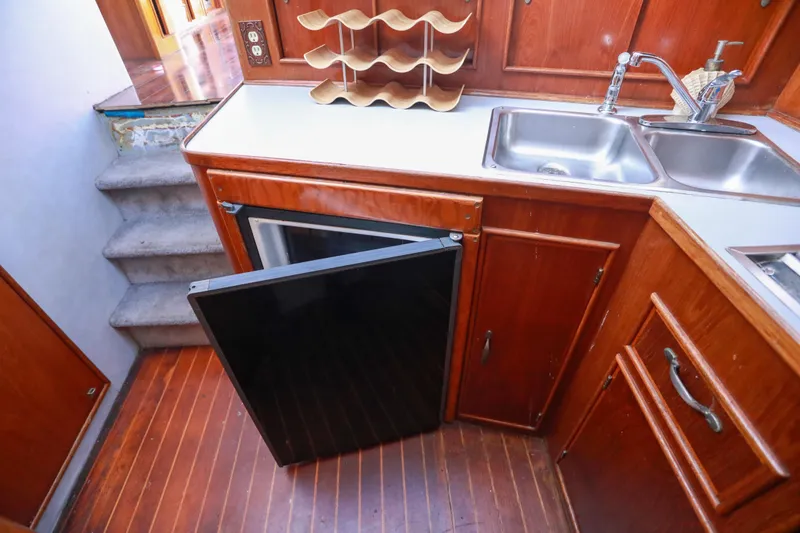 Slide: The Image of 1987 Mediterranean 38 yacht kitchen with wooden cabinets, sink, and open fridge. - 18