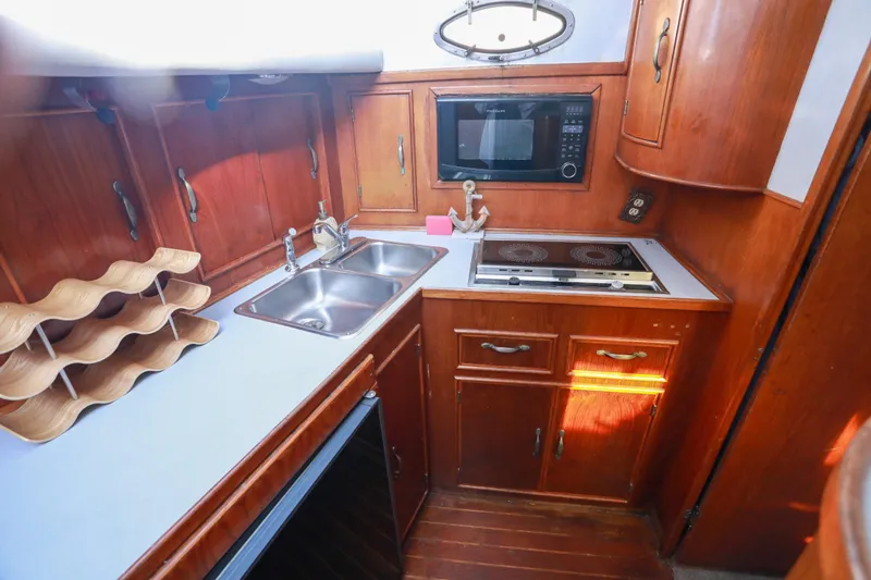 Slide: The Image of Compact 1987 Mediterranean 38 yacht kitchen with wooden cabinetry, dual sink, microwave, and stove. - 19