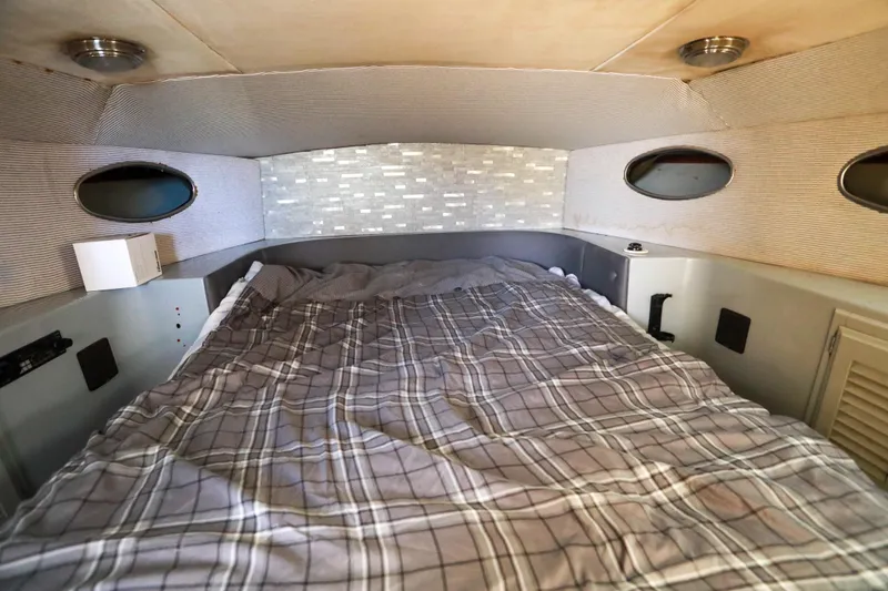 Slide: The Image of Cozy cabin interior of a 1987 Mediterranean 38 boat with plaid bedding and porthole windows. - 24