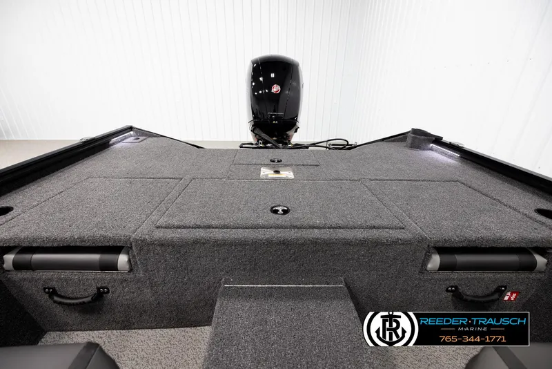 Slide: The Image of 2025 Lund 1975 Renegade boat interior with motor, featuring carpeted deck and storage compartments. - 17