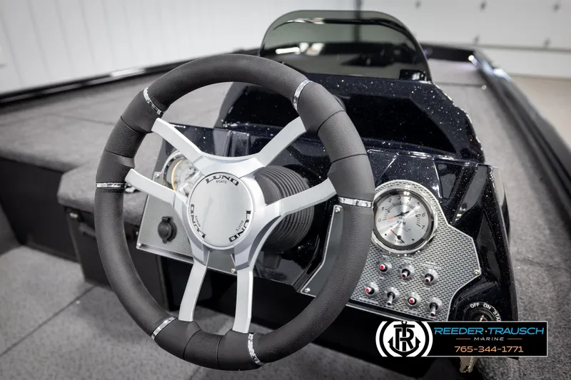 Slide: The Image of Steering wheel and dashboard of 2025 Lund 1975 Renegade boat, featuring modern controls. - 25
