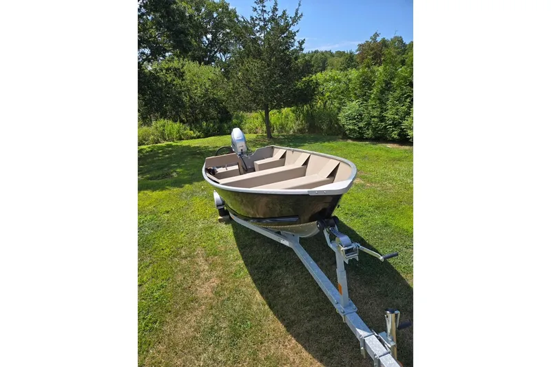 Slide: The Image of 2024 Polar Kraft Dakota boat on trailer in grassy area, surrounded by trees. - 1