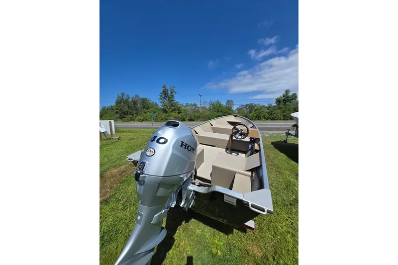 Slide: The Image of 2024 Polar Kraft Dakota boat with Honda motor on grassy area under clear blue sky. - 4