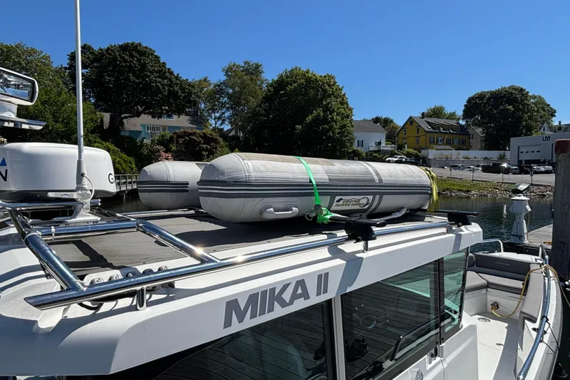 Slide: The Image of 2020 Axopar 29 Aft Cabin with inflatable boat on roof, docked by waterfront homes. - 11