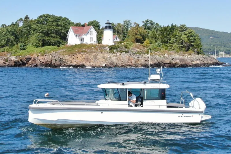 Slide: The Image of 2020 Axopar 28 Cabin near coastal landscape with lighthouse. - 2