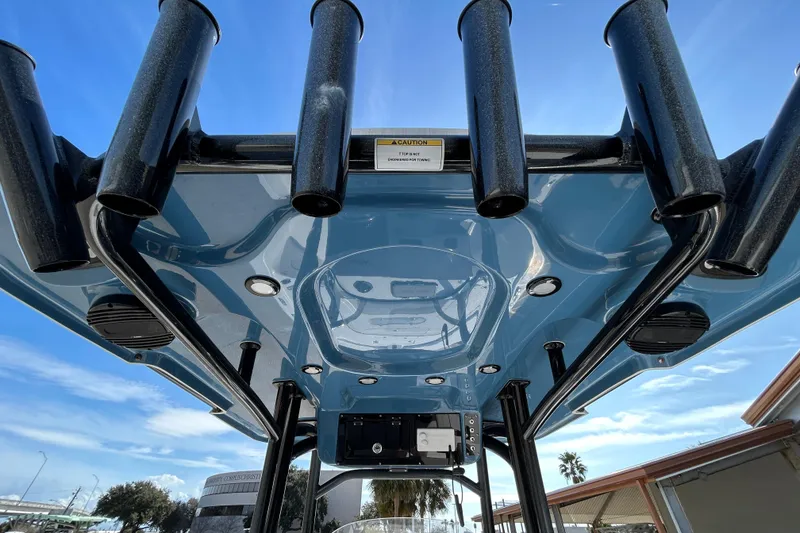 Slide: The Image of 2026 Sea Pro 250 Bay boat's T-top with rod holders and electronics, under a clear blue sky. - 13