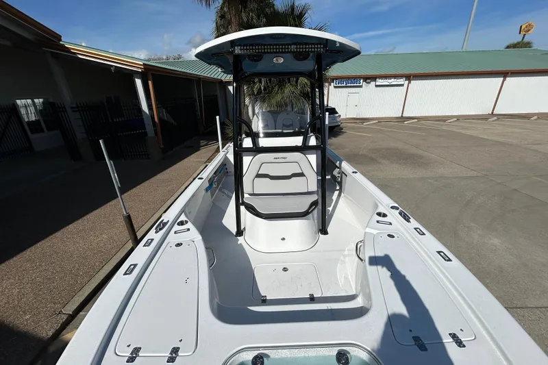 Slide: The Image of 2026 Sea Pro 250 Bay boat, white interior, parked outdoors under clear sky. - 22