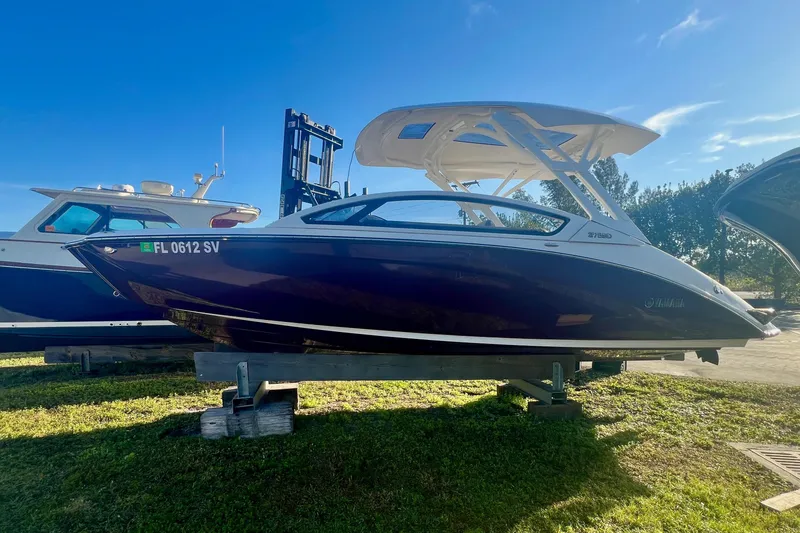 The Image of 2021 Yamaha Boats 275SD on calm water with lush greenery backdrop. - 0