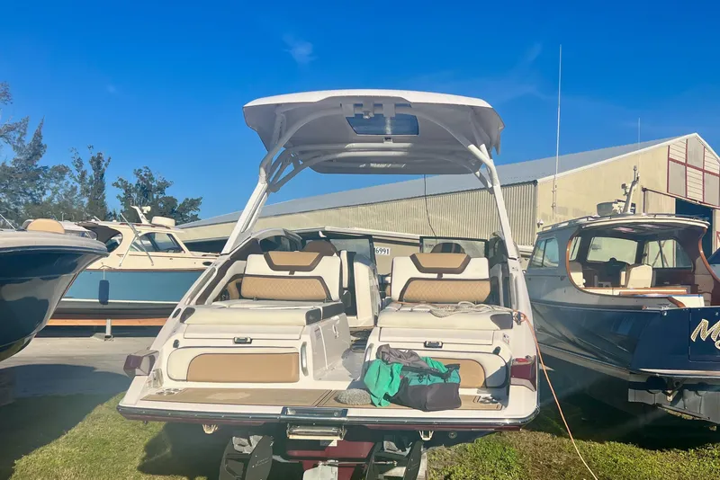 Slide: The Image of 2021 Yamaha Boats 275SD in water, docked near lush greenery. - 2