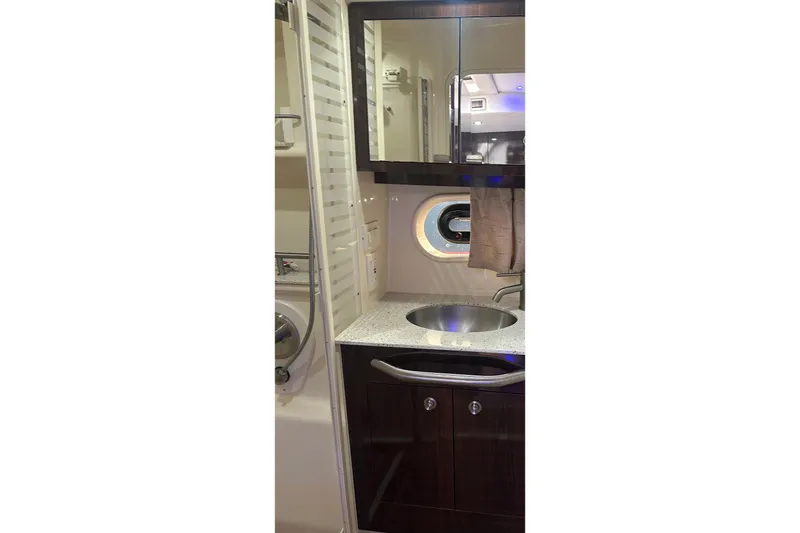 Slide: The Image of 2016 Searay Sundancer 370 bathroom with sink, mirror, and porthole window. - 15