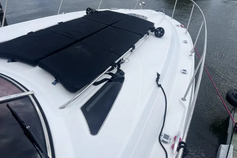 Slide: The Image of 2016 Searay Sundancer 370 boat deck with black cushions, docked on calm water. - 16