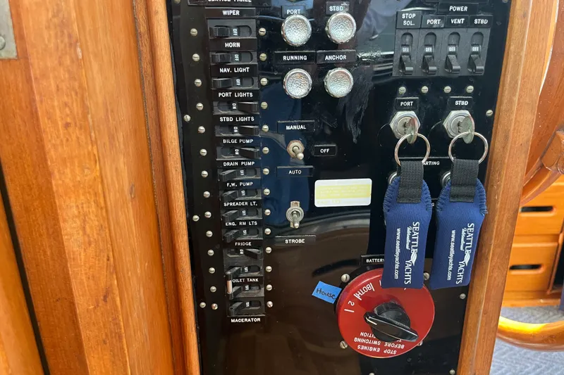 Slide: The Image of Control panel of a 1979 Grand Banks 36 Classic yacht with labeled switches and keys. - 56