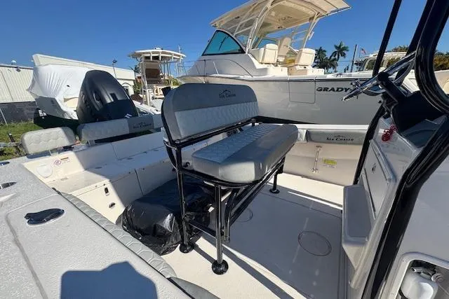 Slide: The Image of 2026 Sea Chaser 22 HFC boat interior with seating and console, docked under clear sky. - 11