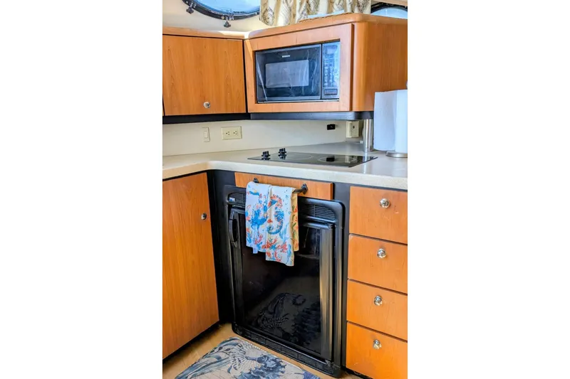 Slide: The Image of 1998 Wellcraft 3600 Martinique yacht kitchen with microwave, stove, and wooden cabinetry. - 7