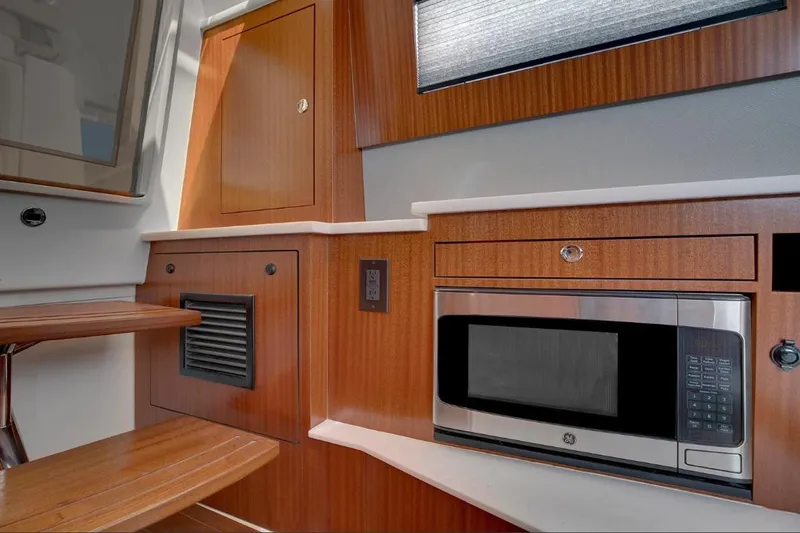 Slide: The Image of Manufacturer Provided Image: 2025 Pursuit S 428 Sport yacht interior with wood cabinetry and built-in microwave. - 20