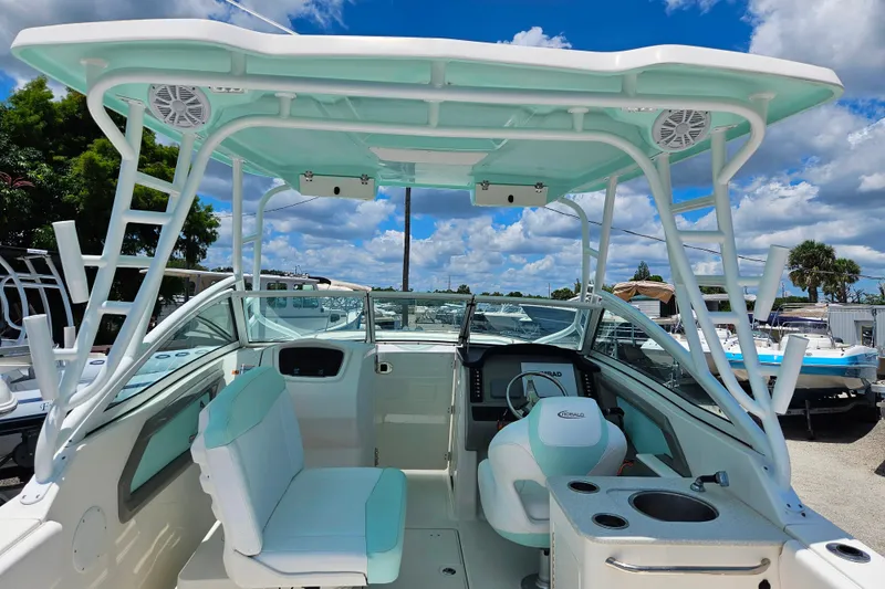 Slide: The Image of 2019 Robalo R247 Dual Console boat interior with seating and helm under a blue sky. - 25