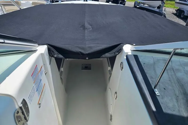Slide: The Image of 2019 Robalo R247 Dual Console boat interior with black cover, open walkway view. - 9