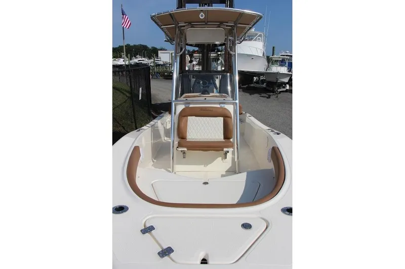 Slide: The Image of 2025 Pioneer 180 Islander boat with tan seating and T-top, docked near other boats. - 4