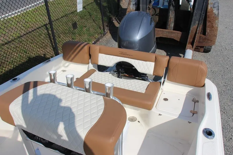 Slide: The Image of 2025 Pioneer 180 Islander boat interior with tan and white seating, docked outdoors. - 7