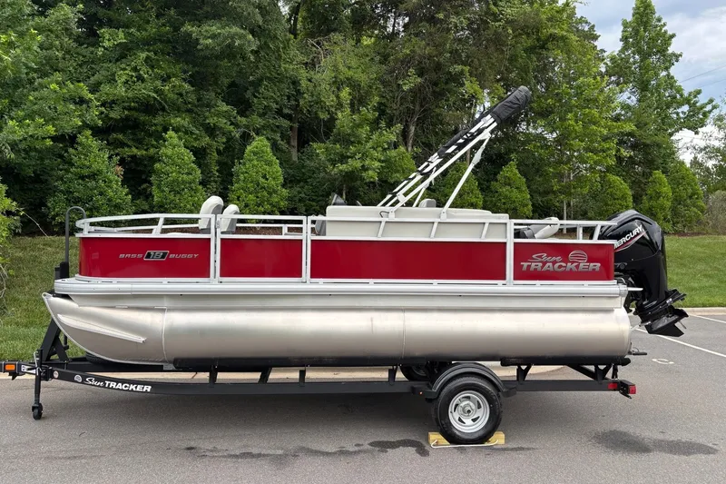 The Image of 2026 Sun Tracker Bass Buggy 18 DLX pontoon boat on trailer, parked outdoors. - 0