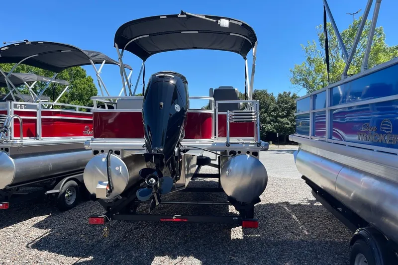 Slide: The Image of 2026 Sun Tracker Bass Buggy 18 DLX pontoon boat with outboard motor, parked outdoors. - 3