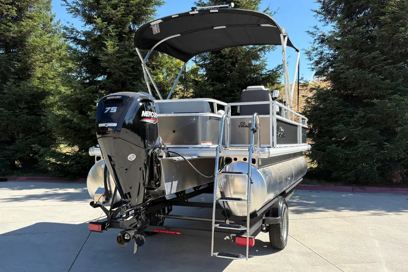 Slide: The Image of 2026 Sun Tracker Bass Buggy 18 DLX pontoon boat with Mercury 75 engine, parked outdoors. - 7