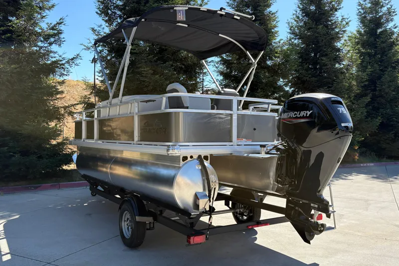 Slide: The Image of 2026 Sun Tracker Bass Buggy 18 DLX pontoon boat with Mercury engine, parked outdoors. - 6