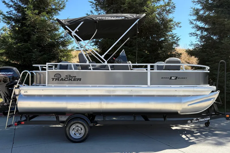 The Image of 2026 Sun Tracker Bass Buggy 18 DLX pontoon boat on trailer, parked outdoors. - 0
