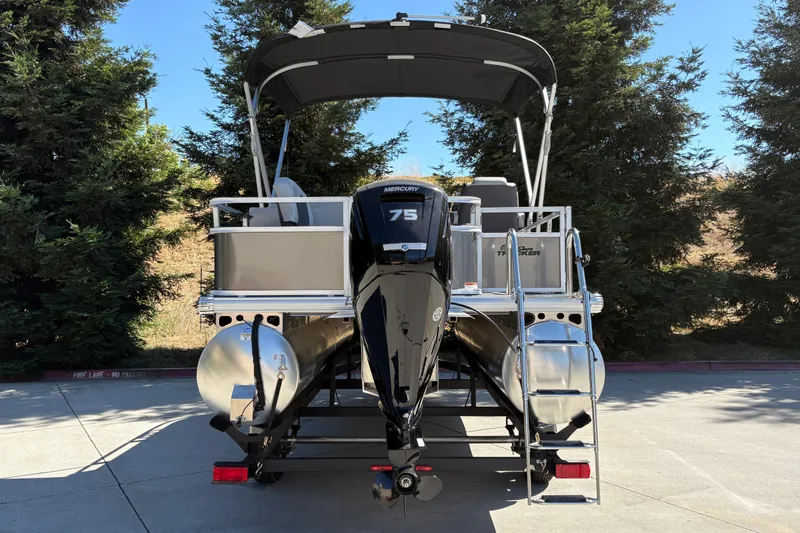 Slide: The Image of 2026 Sun Tracker Bass Buggy 18 DLX pontoon boat with Mercury 75 engine, parked outdoors. - 8