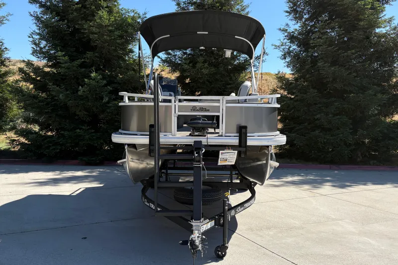Slide: The Image of 2026 Sun Tracker Bass Buggy 18 DLX pontoon boat on trailer, parked outdoors. - 3