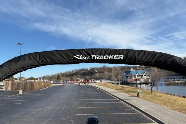 Slide: The Image of 2026 Sun Tracker Bass Buggy 18 DLX boat canopy in a lakeside parking area. - 101