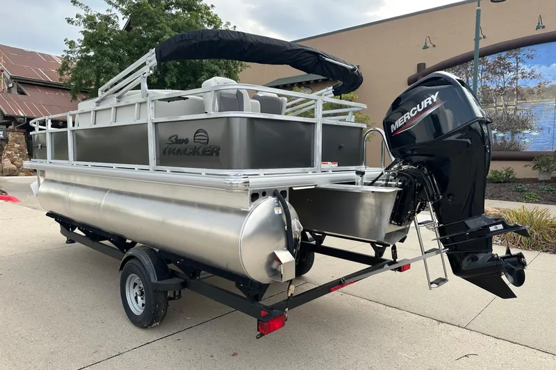 Slide: The Image of 2026 Sun Tracker Bass Buggy 18 DLX pontoon boat with Mercury outboard motor on trailer. - 2